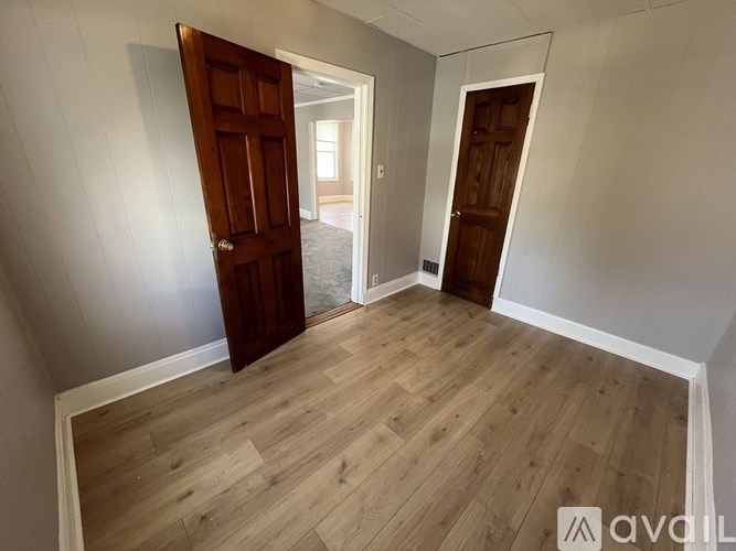 A room with wooden floors and two doors, one of which is open.
