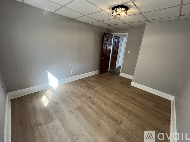 A room with wooden flooring and a door on the right side.