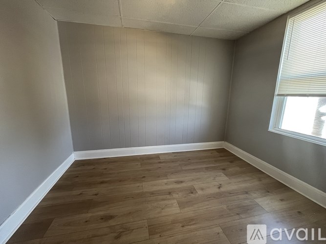 Empty room with wooden flooring and a window.