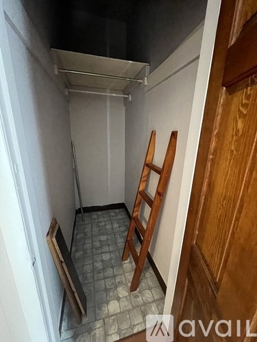 A small, empty room with a wooden ladder against the wall.