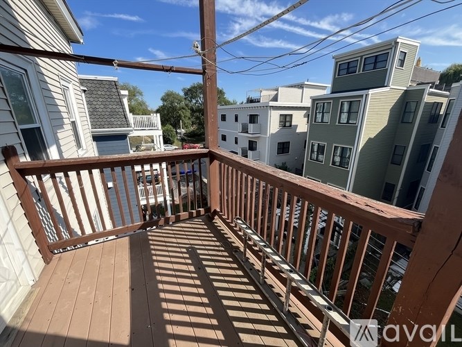 A wooden deck with a railing and a view of the street and buildings.