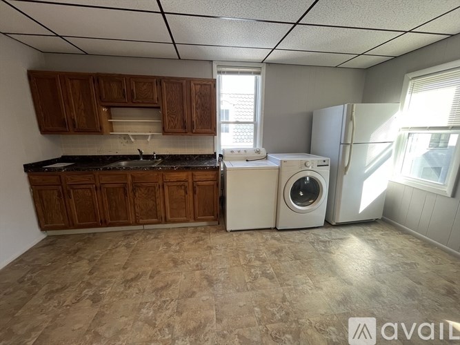 A kitchen with wooden cabinets and a washer and dryer.