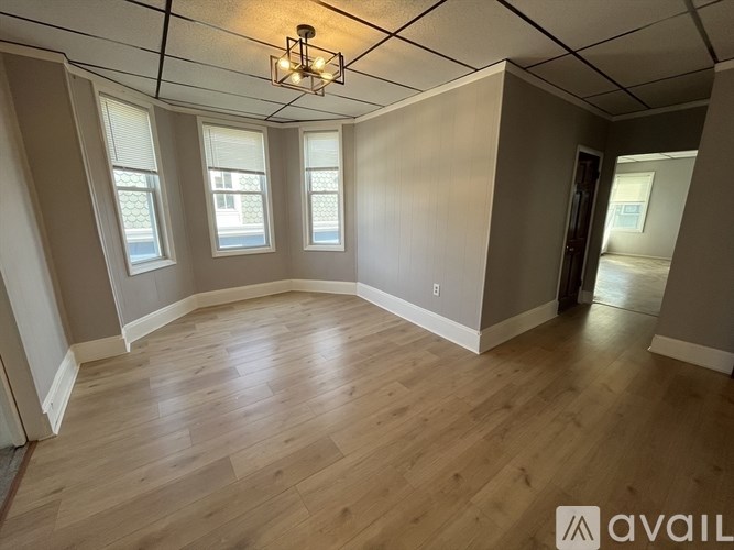 A room with wooden flooring and a chandelier hanging from the ceiling.