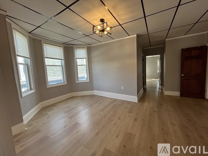A room with wooden flooring and a ceiling with a grid pattern.