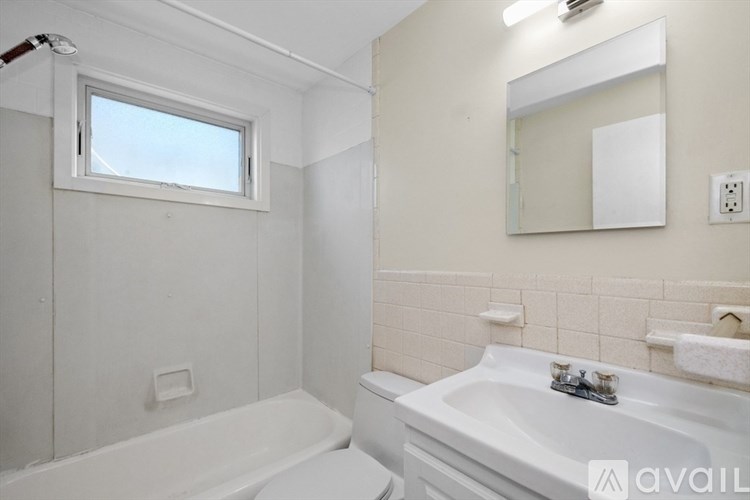 A white bathroom with a tub, sink, and mirror.