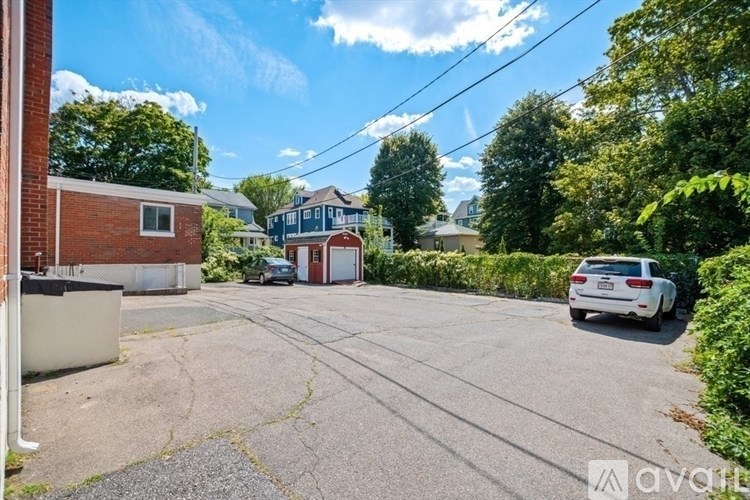 A car is parked in a driveway with a house and trees in the background.
