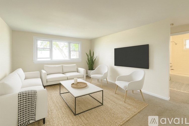 A living room with a white couch, a black TV, and a plant.