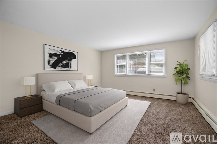 A bedroom with a large bed, a nightstand, a carpet, a potted plant, and a framed picture on the wall.