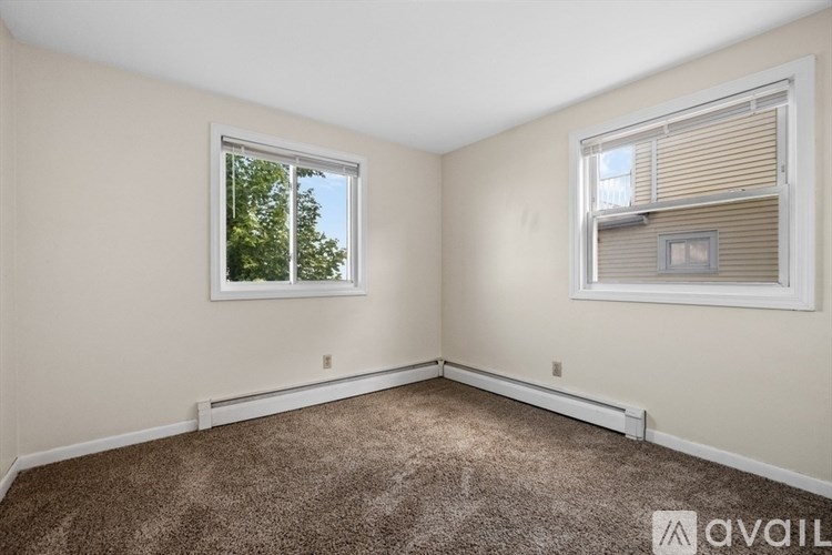 A room with a carpeted floor and two windows.
