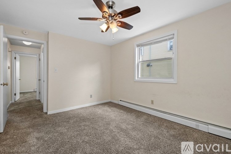 A room with a ceiling fan and a window with blinds.