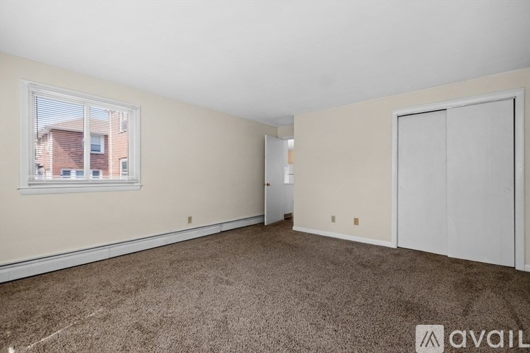 A room with a carpeted floor and a window showing a building outside.