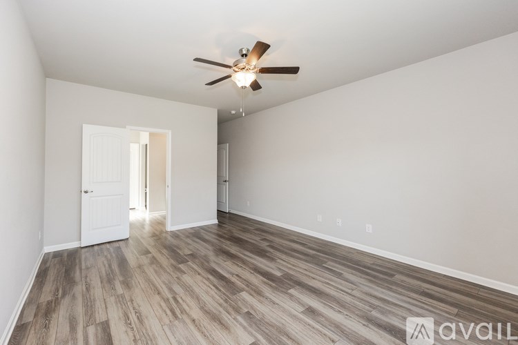 A room with a ceiling fan and wooden flooring.