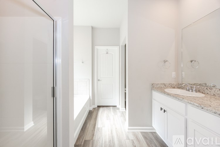A bathroom with a sink, mirror, and wooden floors.