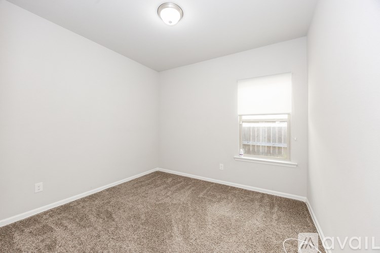 A room with a carpeted floor and a window with blinds.