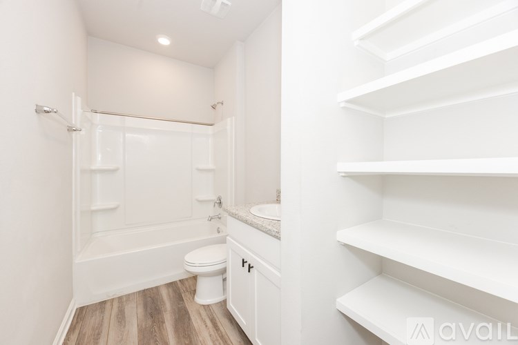 A white bathroom with a toilet, sink, and shelves.