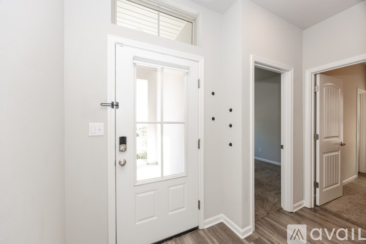 A white door with a window and a handle is in a room.