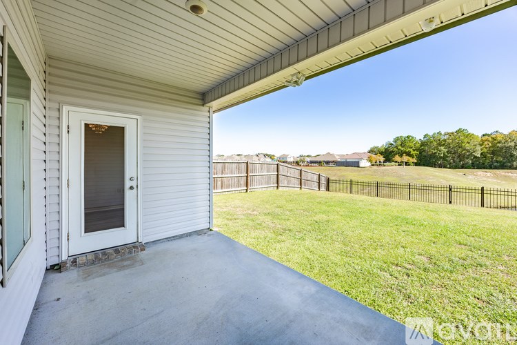 A patio area with a white door and a view of a fenced yard.