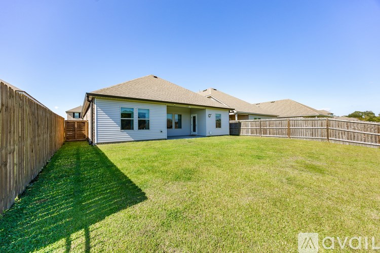 A house with a white exterior and a brown roof is surrounded by a wooden fence.