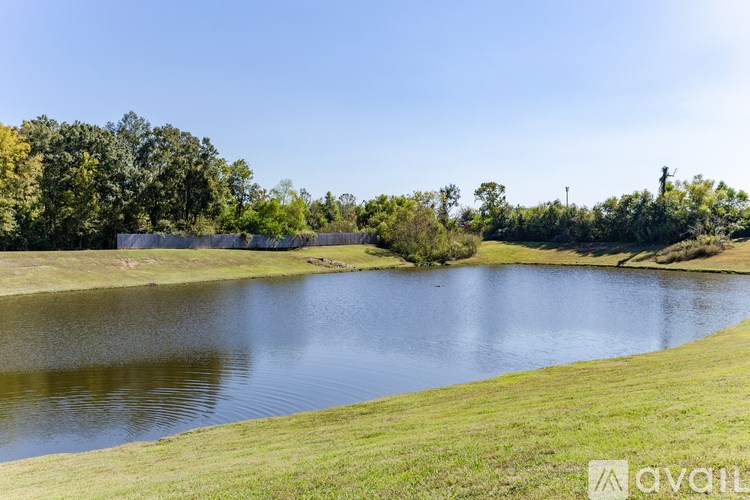A serene lake surrounded by lush greenery under a clear blue sky.