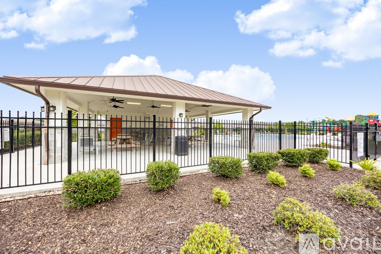 A small building with a brown roof and a black fence in front of it.