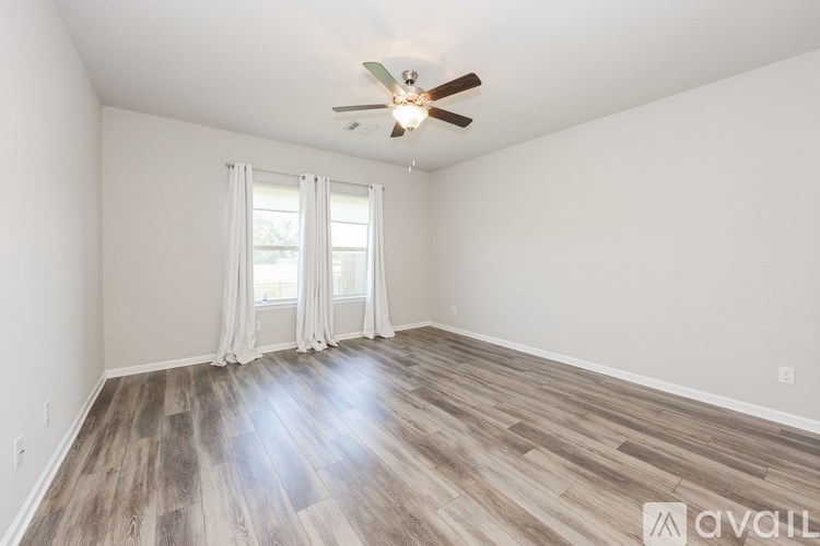 A room with a ceiling fan and wood flooring.