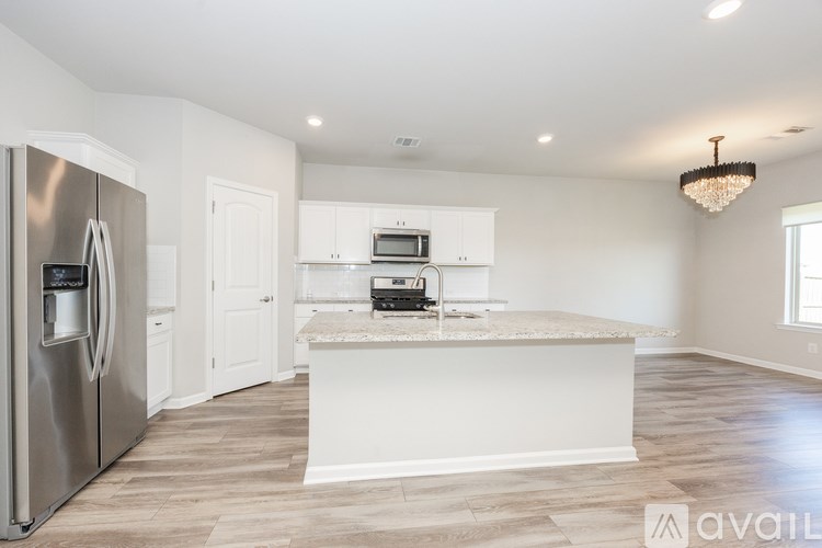 A modern kitchen with a stainless steel refrigerator and a central island with a built-in microwave and oven.
