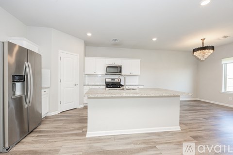 A modern kitchen with a stainless steel refrigerator and a central island with a built-in microwave and oven.