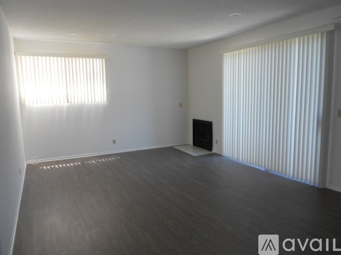 A spacious room with wooden flooring and a black speaker on the floor.