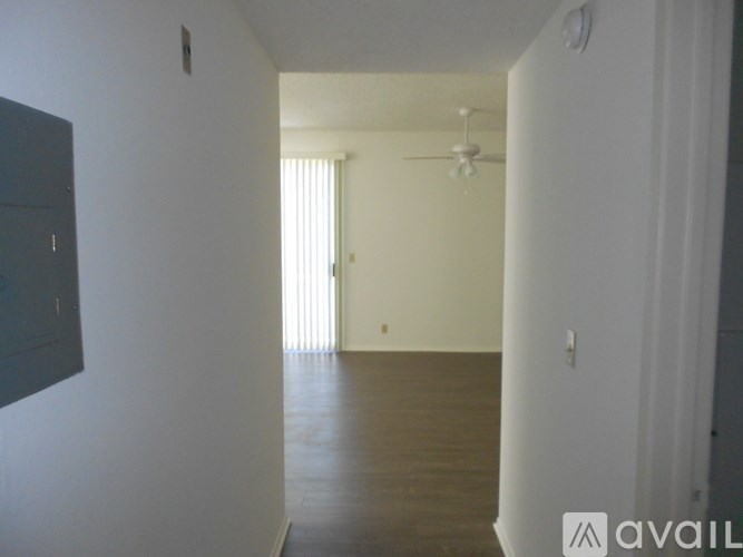 A room with a ceiling fan and a door leading to a hallway.