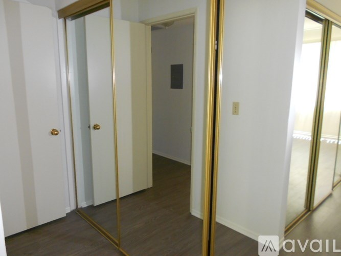 A white door with a gold handle is reflected in a large mirror.