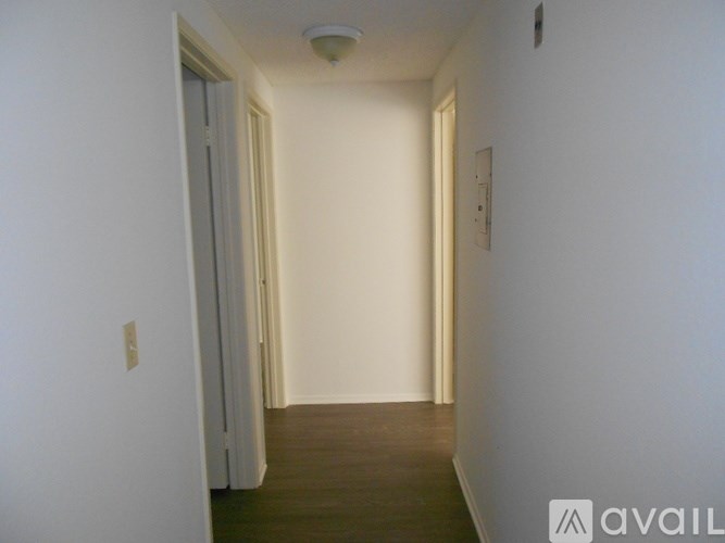 A long hallway with a door on the left and a light switch on the wall.