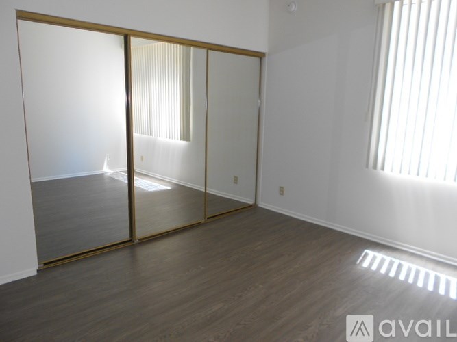 A room with a wooden floor and a large mirror on the wall.