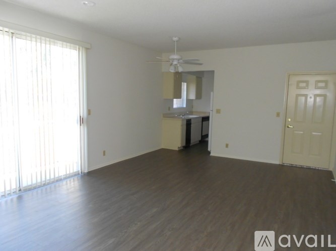 A spacious room with wooden flooring and a ceiling fan.