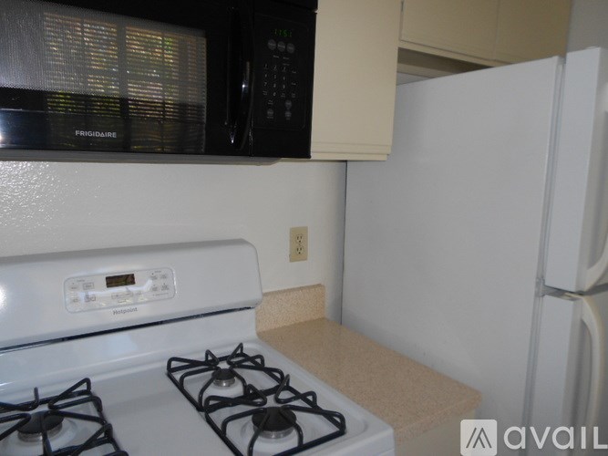 A white stove top with a white fridge in the background.