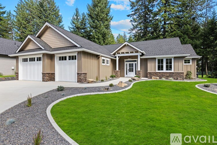 A house with a brown and beige exterior and a stone wall.
