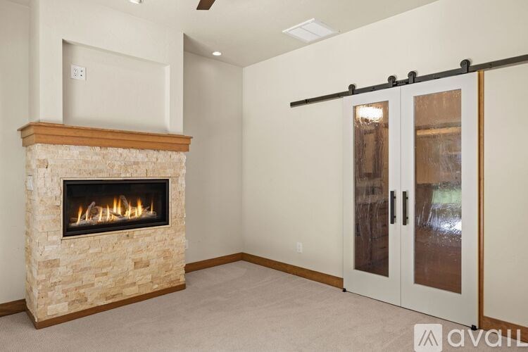 A modern living room with a stone fireplace and sliding glass doors.