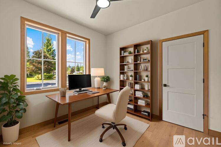 A room with a desk, chair, and a window with a view of the outside.