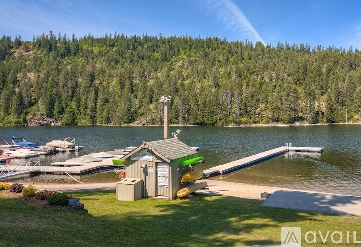 A small boathouse sits on the shore of a lake with boats docked nearby.