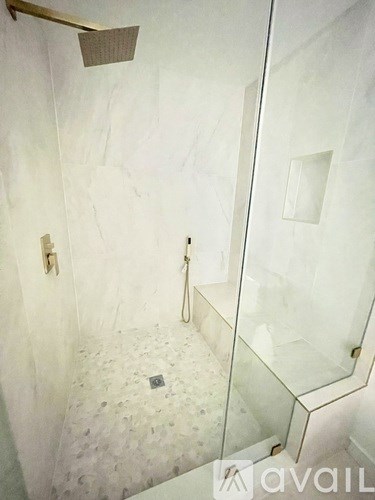 A bathroom with a glass shower door and a marble floor.