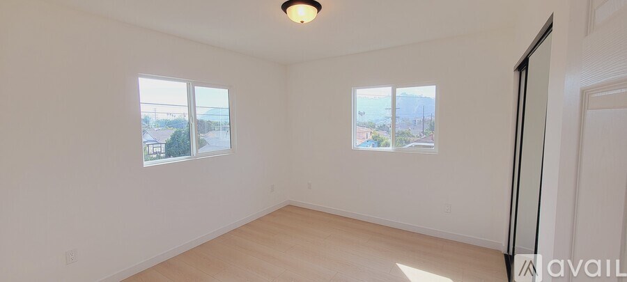 A room with two windows and a door is available for rent.