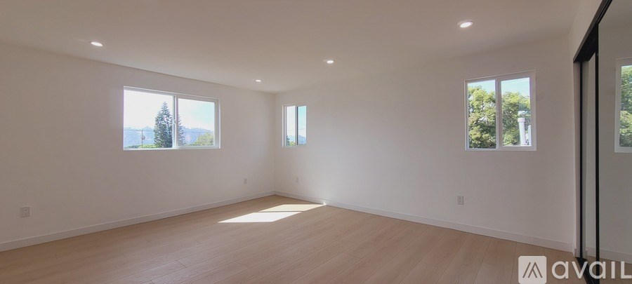 A large empty room with wooden floors and windows.