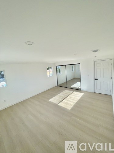 A spacious room with wooden flooring and a white door.
