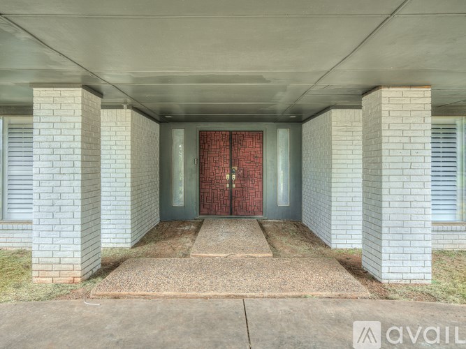 A red door is in the middle of a concrete hallway.
