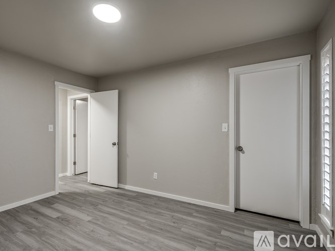 A room with a white door and a wooden floor.