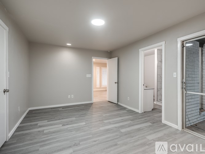 A spacious room with wooden flooring and white walls.