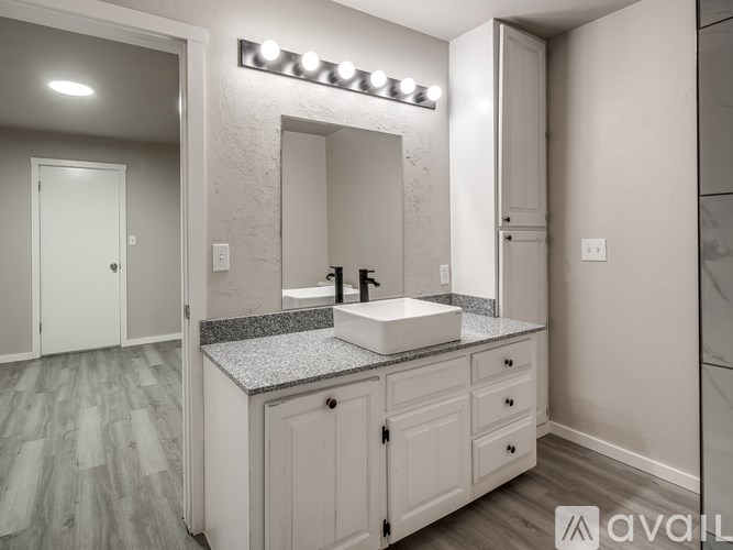 A bathroom with a vanity and a mirror with lights above it.