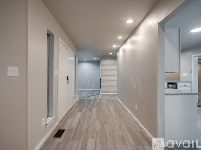 A long, narrow hallway with wood flooring and white walls.
