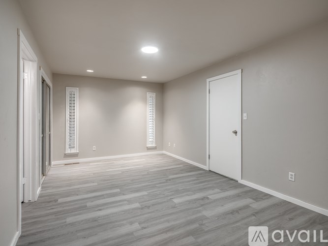 A spacious room with wooden flooring and white walls.