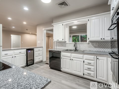 A modern kitchen with white cabinets and a black countertop.