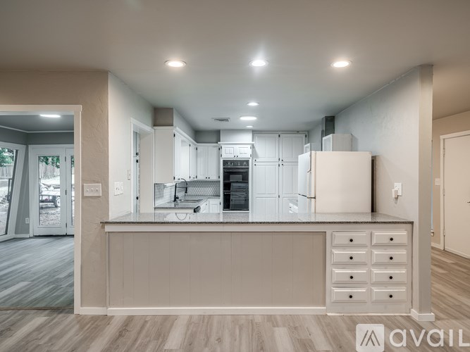 A modern kitchen with a white refrigerator and wooden flooring.